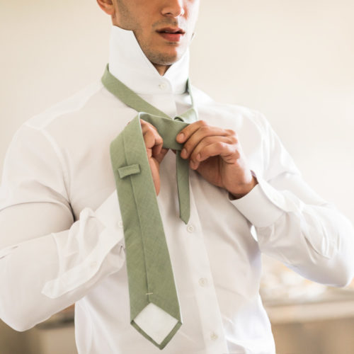 Groom doing up tie.