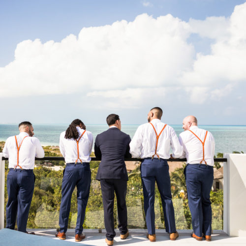 Groomsmen looking off to ocean on rooftop deck at Finest Playa Mujeres