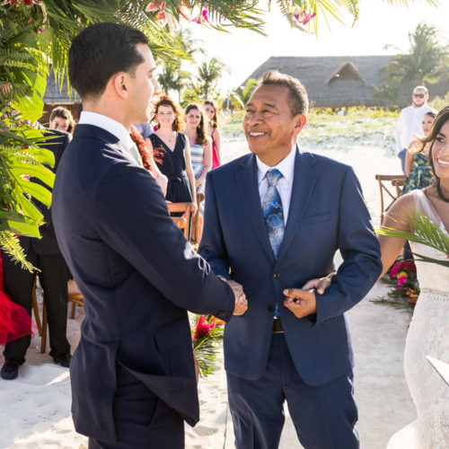 Groom shaking hands with father of bride at wedding ceremony.