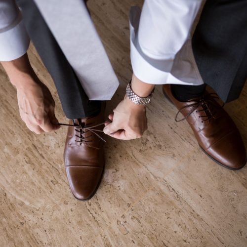Groom tying up shoes.