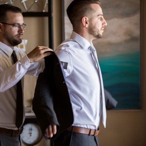 Groomsman helping groom put on jacket at NOW Sapphire Riviera Maya Resort