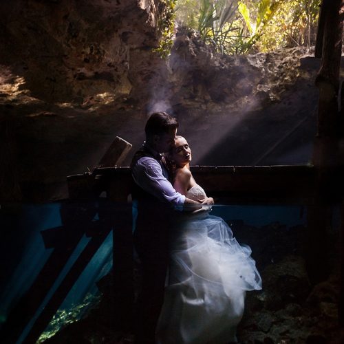 Bride and groom half underwater and above in romantic pose in Cenote Trash the Dress