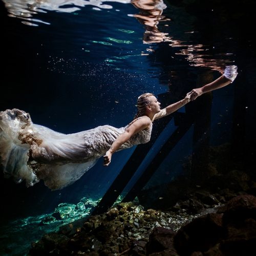 Bride reaching for grooms hand in underwater Mayan Cenote Trash the Dress