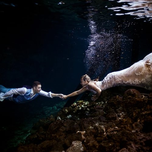Bride and groom underwater reaching for each other in Mayan Cenote Trash the Dress
