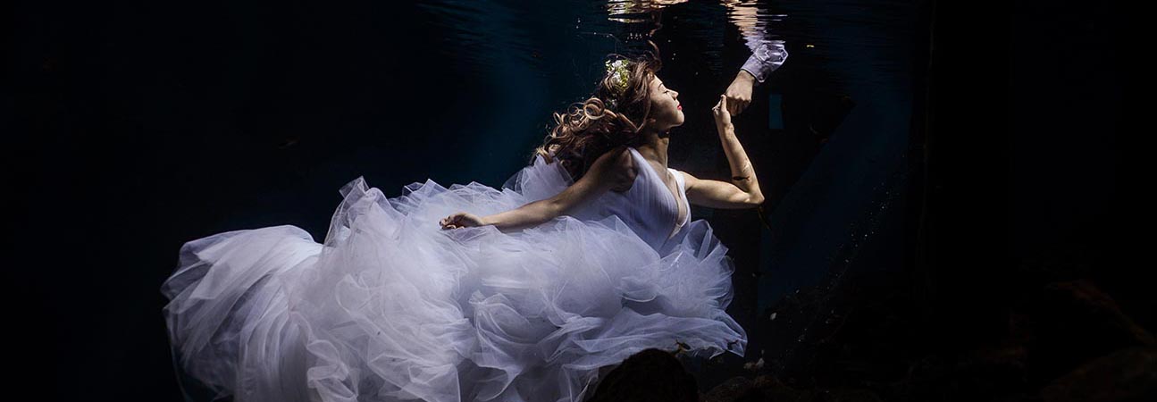 Bride reaching for Groom in underwater trash the dress