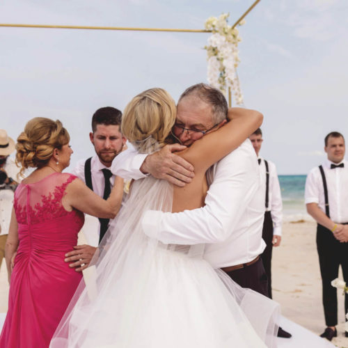 Bride giving emotional hug to father after walking down the aisle at iberostar paraiso beach resort