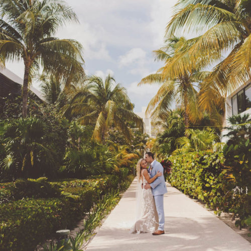 Wide angle photograph of bride and groom in the gardens at Finest Playa Mujeres