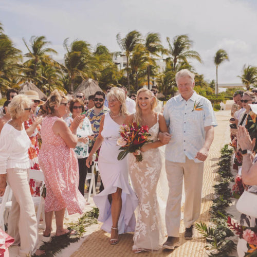 Bride walking down aisle with mother and father at beach wedding at Finest Playa Mujeres