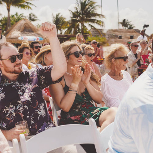 Guests clapping at wedding ceremony on beach