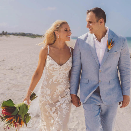 Jamie and Anthony walking on beach smiling after wedding at Finest Playa Mujeres