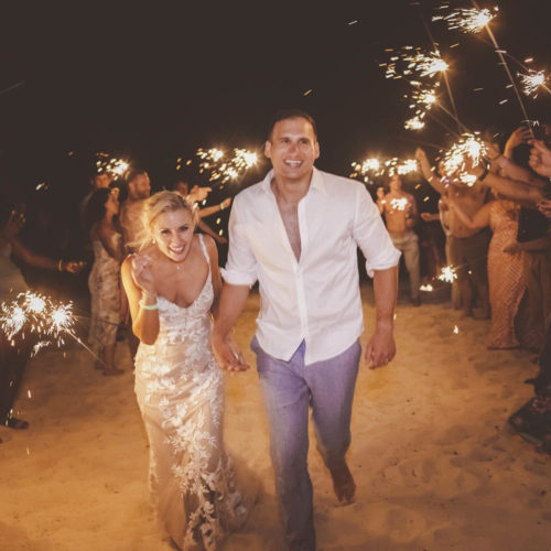 Bride and groom walking through sparklers after wedding atFinest Playa Mujeres