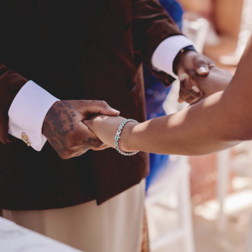 Close up of bride and groom holding hands during wedding ceremony.