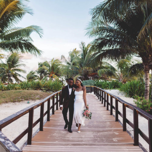 Wide angle photograph of bride and groom walking on paths at Royalton Riviera Cancun Resort