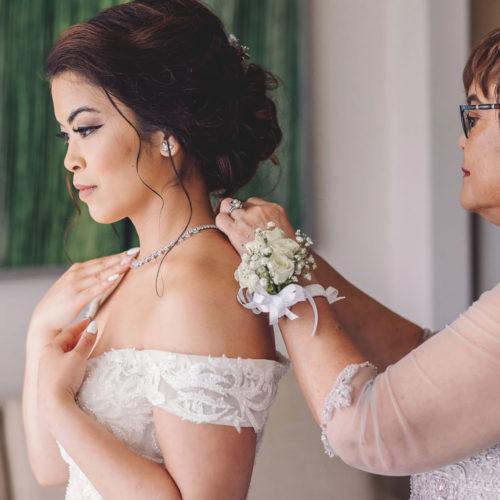 Mother helping bride put on necklace at Royalton Riviera Cancun