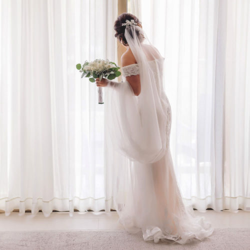 Bride trying to look outside to the ceremony location from her hotel room at Royalton Riviera Cancun