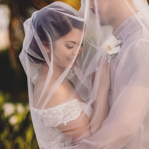 Bride and groom under veil.
