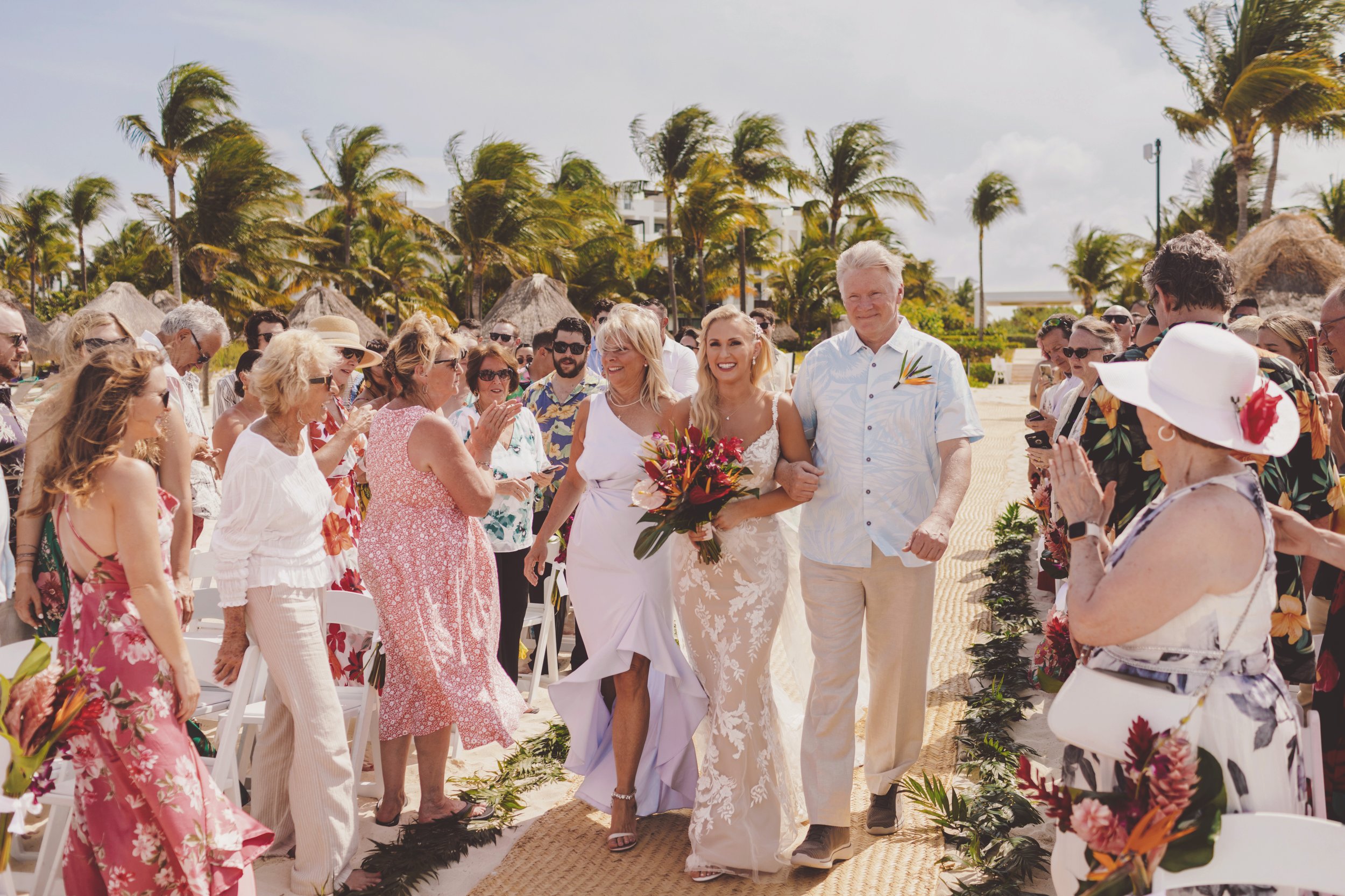 Mother and father walking bride down aisle at wedding in Cancun.