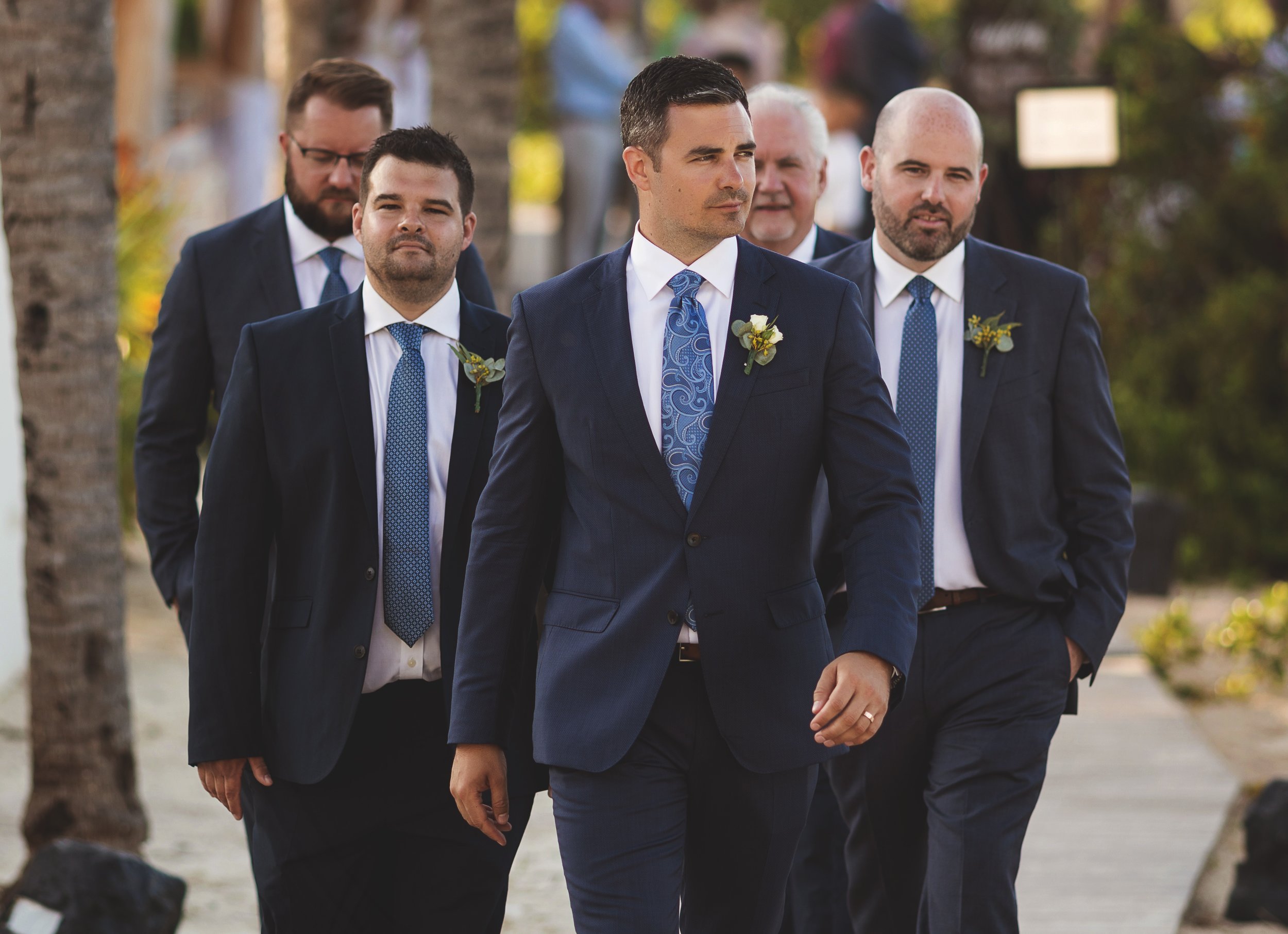 Groom with groomsmen walking on walkway at their Cancun wedding