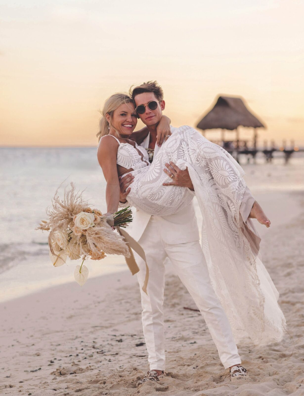 groom carrying bride on beach in Cancun, Mexico